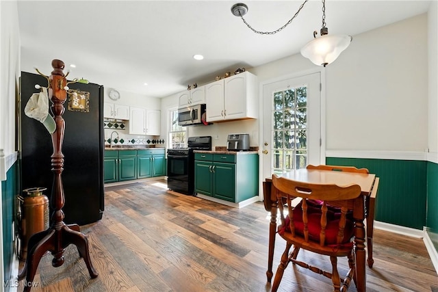 kitchen with wood finished floors, green cabinets, white cabinets, black appliances, and a sink