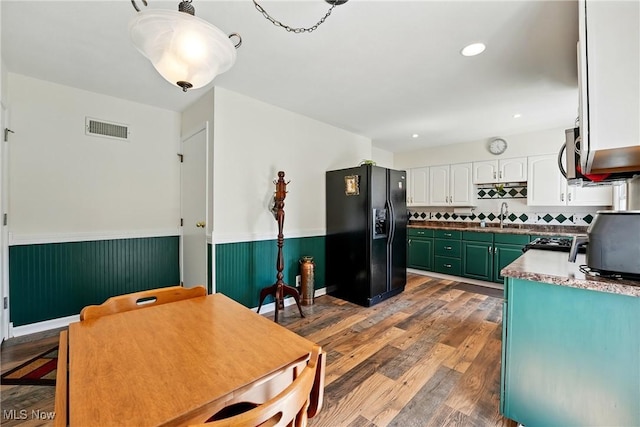 kitchen with visible vents, wainscoting, wood finished floors, and black fridge