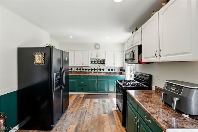 kitchen featuring a sink, green cabinets, light wood-type flooring, black appliances, and white cabinetry