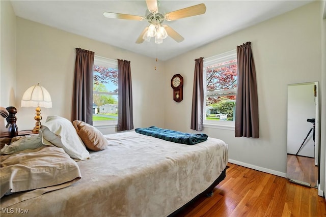 bedroom with a ceiling fan, light wood-style flooring, and baseboards