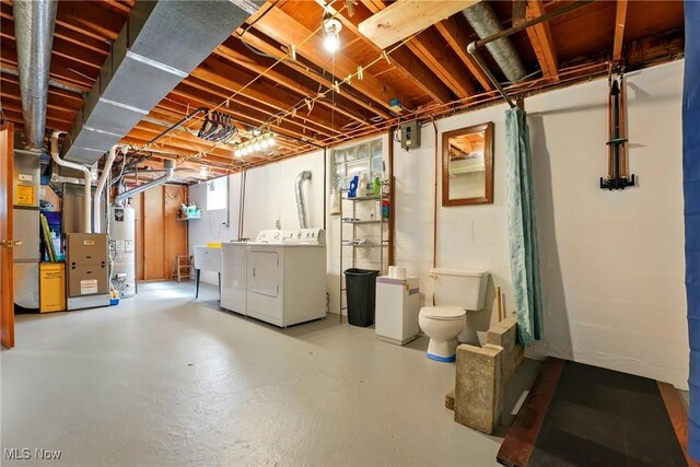 unfinished basement with heating unit, water heater, and washing machine and dryer