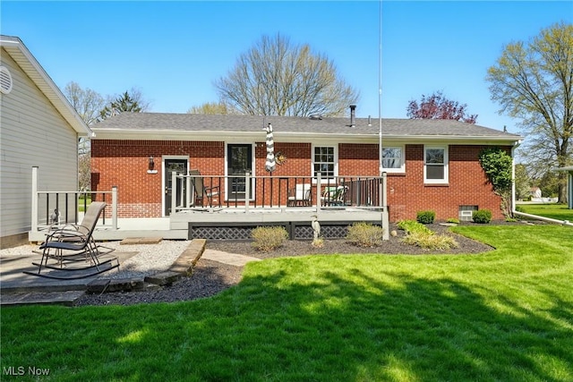 rear view of house featuring a lawn, a wooden deck, and brick siding