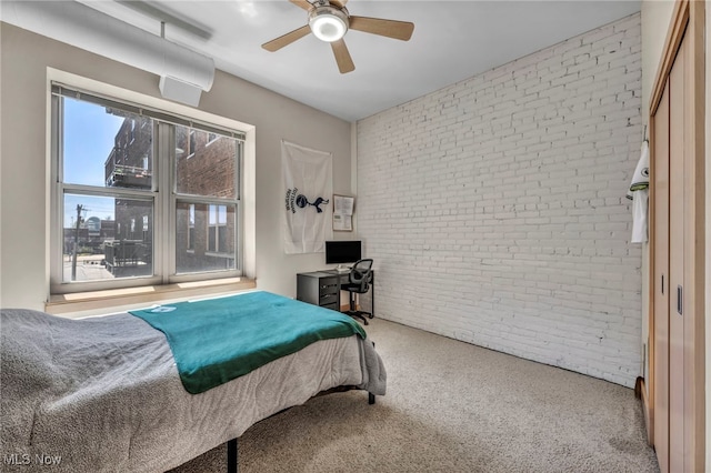 bedroom featuring ceiling fan, carpet, and brick wall
