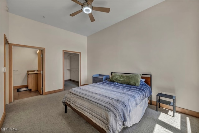 bedroom with connected bathroom, ceiling fan, baseboards, carpet floors, and a spacious closet
