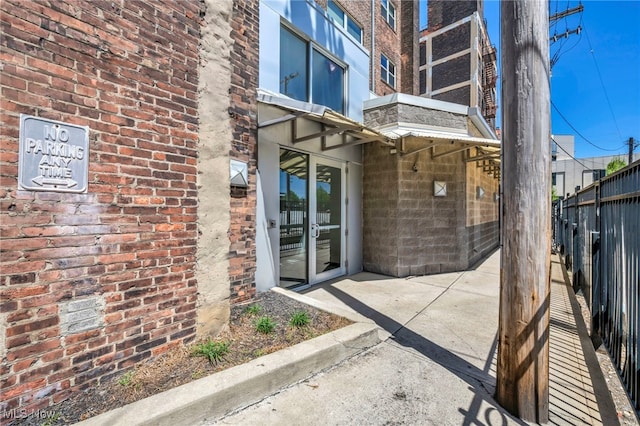 property entrance with a patio, brick siding, and fence