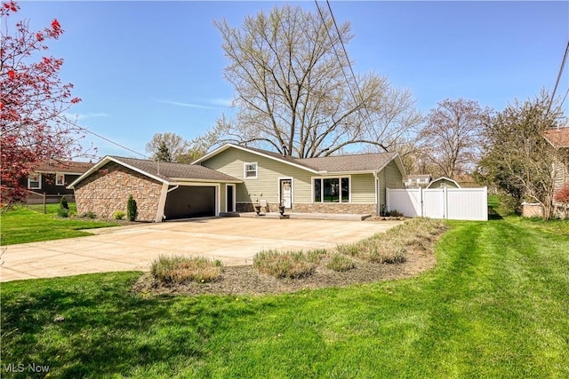exterior space with a garage, fence, a yard, and stone siding