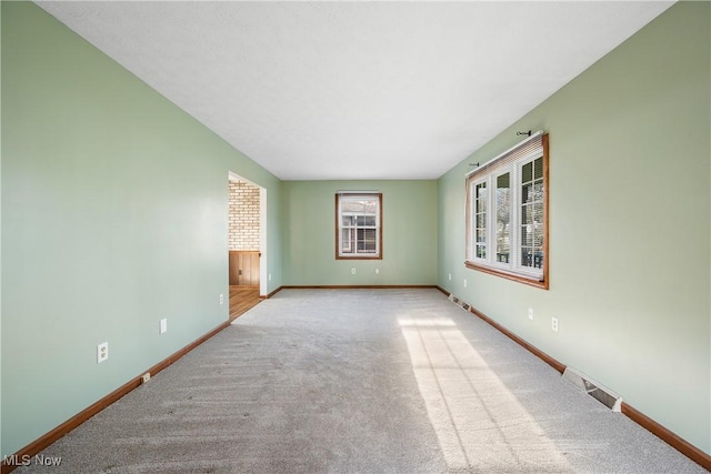 empty room with baseboards, visible vents, and carpet