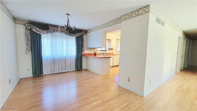 813 Brentwood Dr, Belpre, OH 45714 - unfurnished dining area featuring light wood-style floors, baseboards, an inviting chandelier, and visible vents