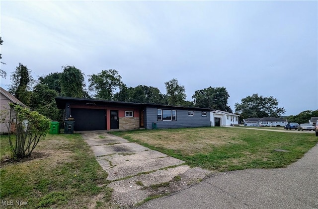 single story home featuring a front yard, driveway, stone siding, and an attached garage