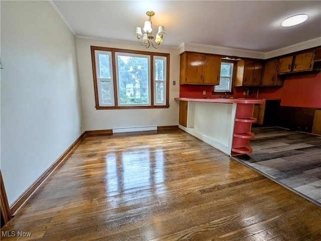 kitchen with a chandelier, a baseboard heating unit, dark wood-style flooring, a peninsula, and crown molding