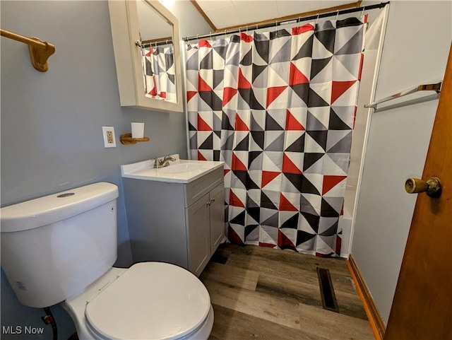 bathroom with toilet, vanity, curtained shower, and wood finished floors