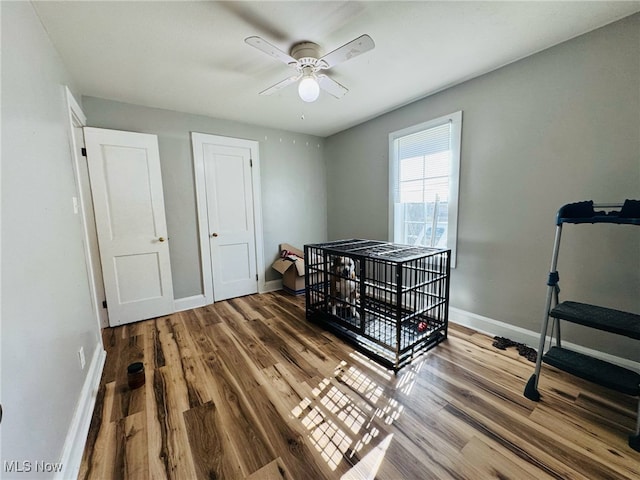 bedroom with ceiling fan, wood finished floors, and baseboards