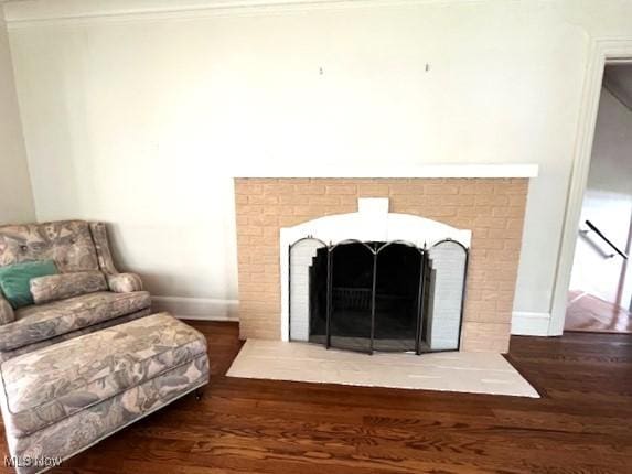 room details with baseboards, a brick fireplace, and wood finished floors
