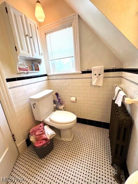 bathroom featuring wainscoting, toilet, and tile walls