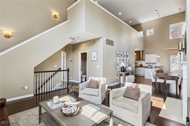 living room featuring dark wood-type flooring, visible vents, and a high ceiling