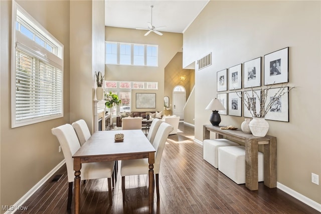 dining room with a towering ceiling, a ceiling fan, visible vents, and baseboards