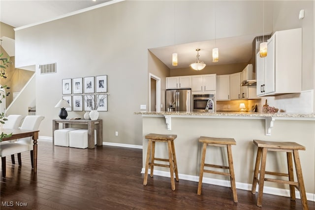 kitchen with light stone countertops, visible vents, white cabinets, appliances with stainless steel finishes, and dark wood finished floors