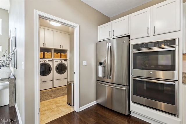 kitchen with dark wood-style flooring, stainless steel appliances, separate washer and dryer, baseboards, and white cabinets