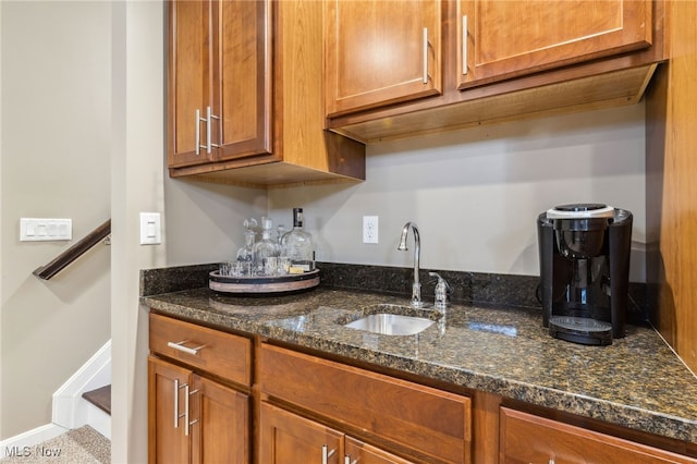 kitchen with dark stone countertops, brown cabinets, and a sink