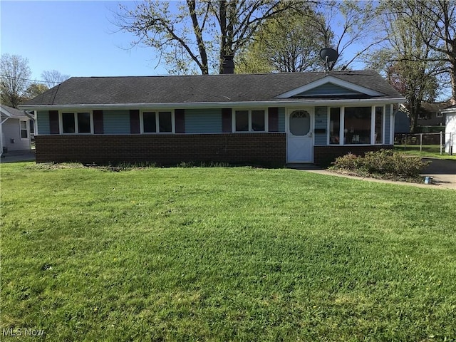 single story home with brick siding, a chimney, a shingled roof, and a front yard