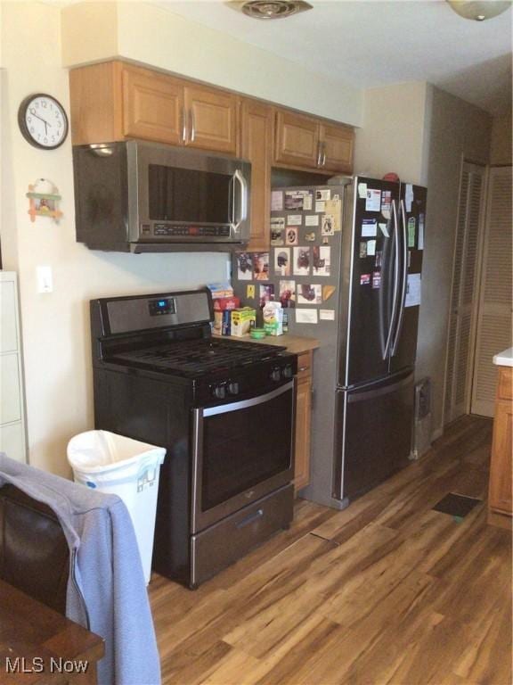 kitchen with appliances with stainless steel finishes, brown cabinetry, and wood finished floors