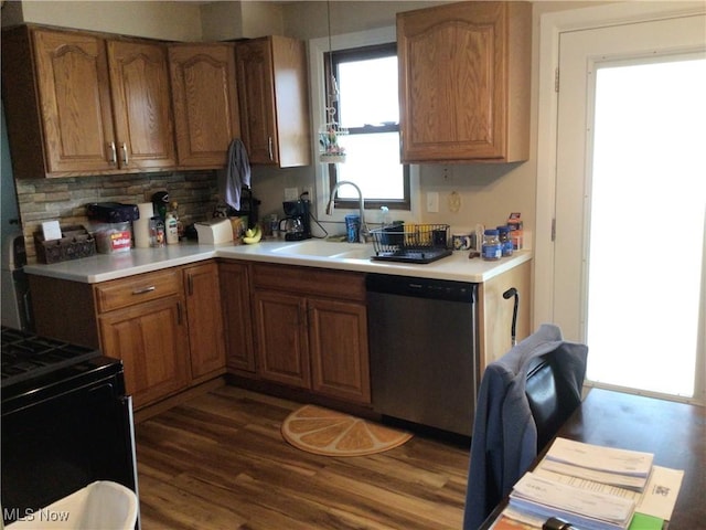 kitchen with stainless steel dishwasher, dark wood-style floors, a sink, and light countertops