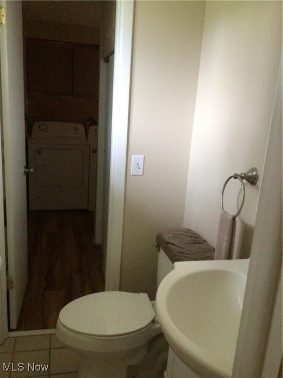 half bath featuring toilet, washing machine and dryer, and a sink