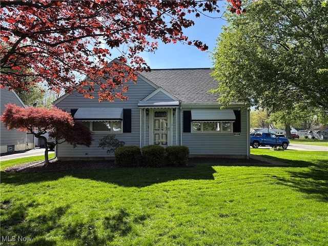 view of front of property with a front yard and roof with shingles