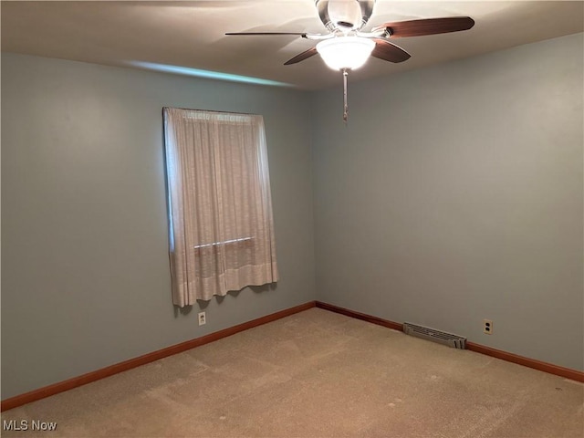 unfurnished room with visible vents, ceiling fan, light colored carpet, and baseboards