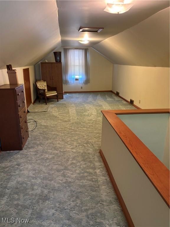 additional living space featuring baseboards, lofted ceiling, and carpet flooring