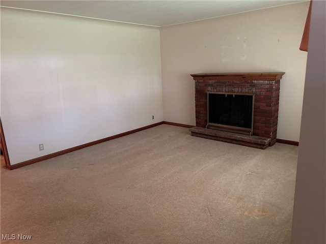 unfurnished living room featuring a brick fireplace, carpet, and baseboards