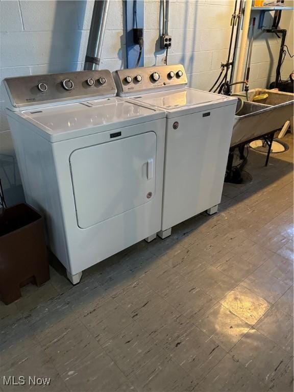 laundry area featuring a sink, washer and clothes dryer, concrete block wall, laundry area, and tile patterned floors