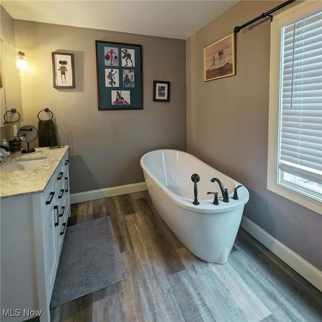 557 Cambridge Rd, Coshocton, OH 43812 - bathroom with baseboards, wood finished floors, a freestanding bath, and vanity
