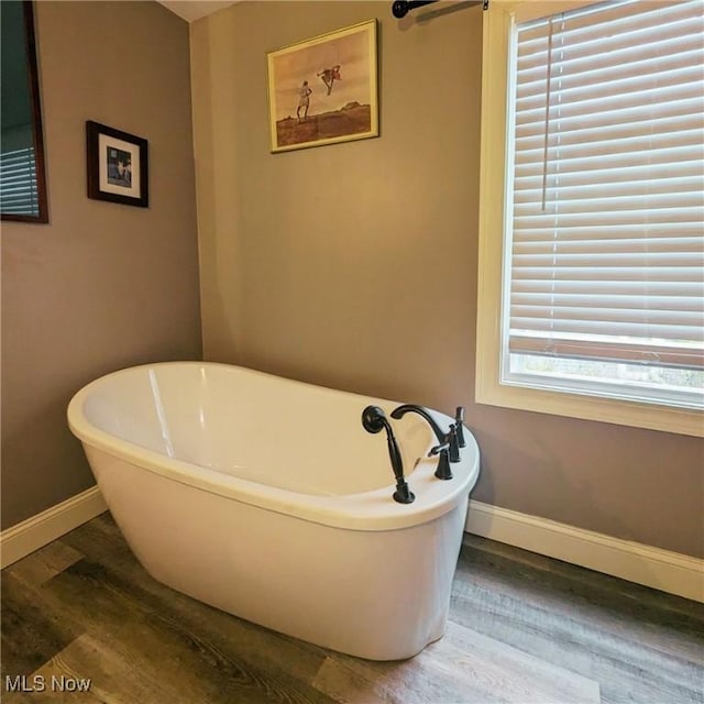 557 Cambridge Rd, Coshocton, OH 43812 - bathroom featuring baseboards, wood finished floors, and a freestanding bath