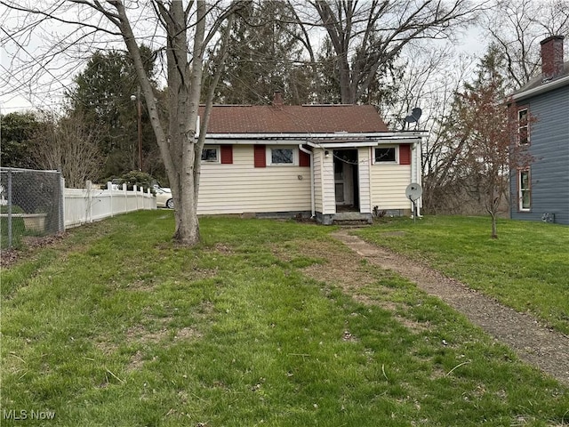 bungalow-style house featuring fence, a chimney, entry steps, and a front lawn