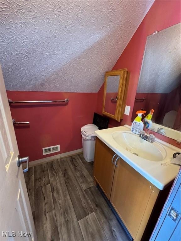 bathroom featuring lofted ceiling, a textured ceiling, visible vents, and wood finished floors