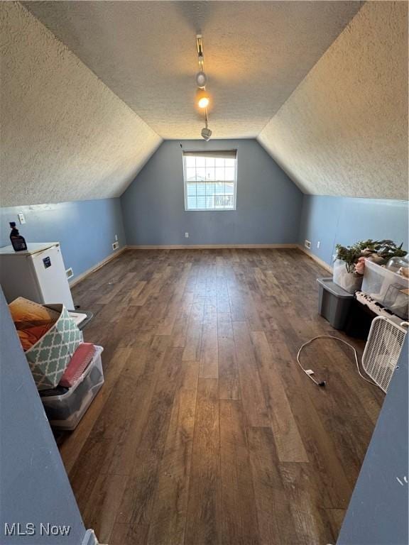 bonus room featuring a textured ceiling, hardwood / wood-style flooring, vaulted ceiling, and baseboards