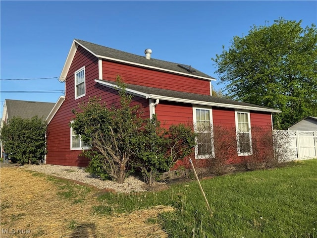 view of home's exterior with a lawn and fence