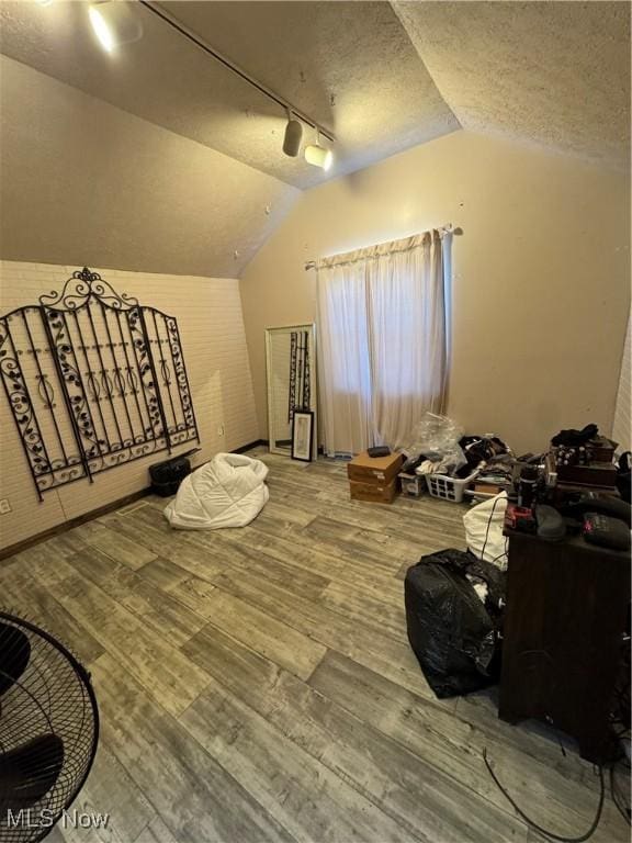additional living space with a textured ceiling, wood finished floors, and vaulted ceiling