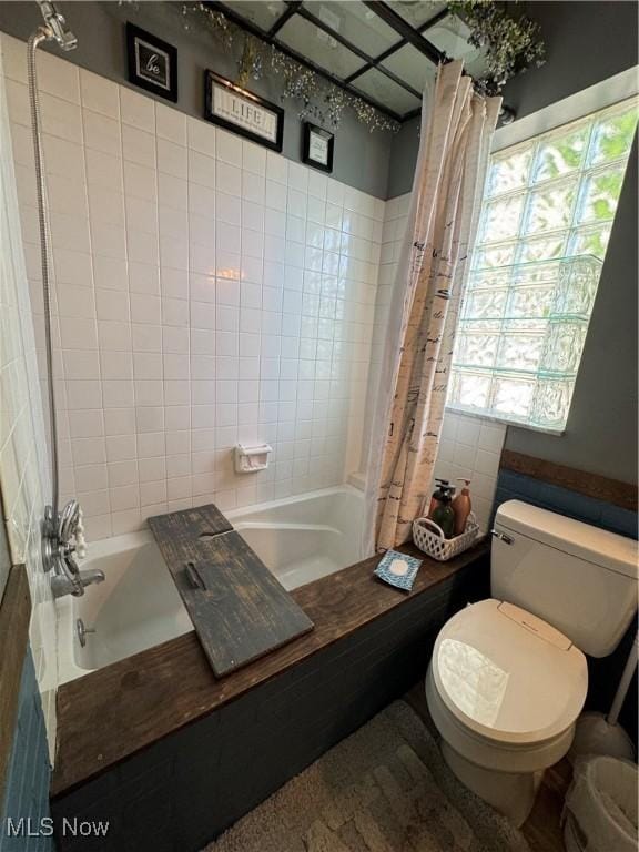 full bath featuring tile walls, toilet, and shower / tub combo with curtain