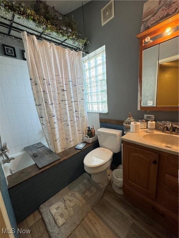 full bathroom with wood finished floors, shower / bath combo with shower curtain, toilet, vanity, and visible vents