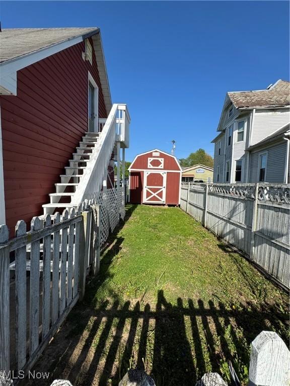 view of yard with an outbuilding, a storage unit, stairway, and a fenced backyard