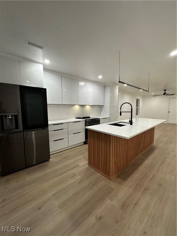 kitchen featuring black appliances, a sink, white cabinetry, visible vents, and modern cabinets