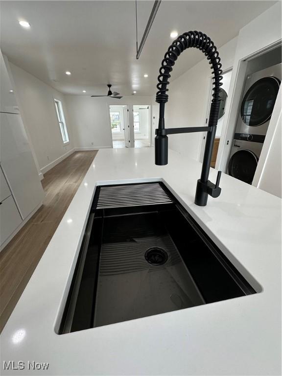 details with a sink, light countertops, stacked washing maching and dryer, recessed lighting, and a ceiling fan