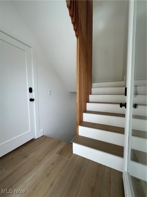 staircase featuring lofted ceiling and wood finished floors