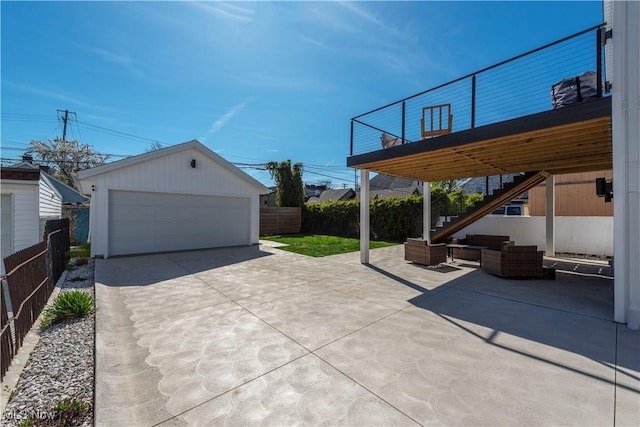 view of patio / terrace featuring an outbuilding, a detached garage, outdoor lounge area, stairs, and fence