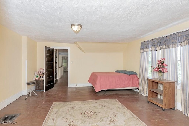 bedroom featuring a textured ceiling, visible vents, and baseboards