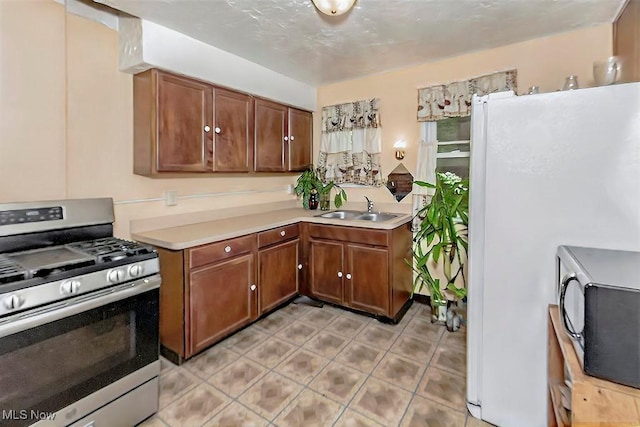 kitchen featuring light tile patterned floors, a sink, black microwave, light countertops, and stainless steel range with gas stovetop