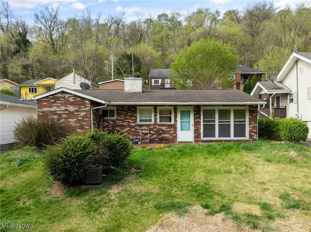view of front of house with a front lawn, a chimney, and brick siding