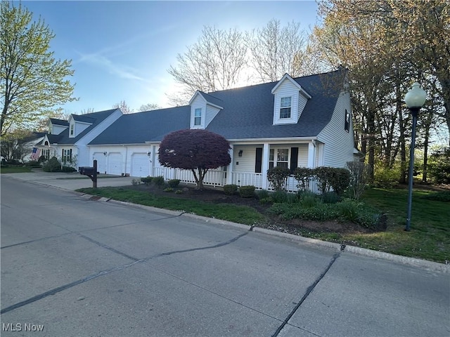 cape cod-style house with a porch, driveway, a garage, and roof with shingles